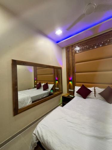a bedroom with two beds and a large mirror at Hotel Blue Wellington - Near Mumbai Airport in Mumbai