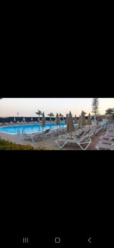 a view of a swimming pool with umbrellas and chairs at BH Cura marina 2 in Mogán
