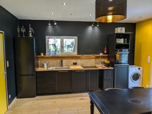 a kitchen with black walls and a black refrigerator at Charme, vue et piscine naturelle in Vedène