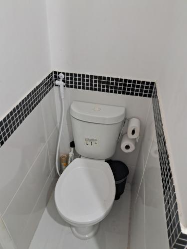 a white toilet in a bathroom with black tiles at Rasa in Cabo Frio
