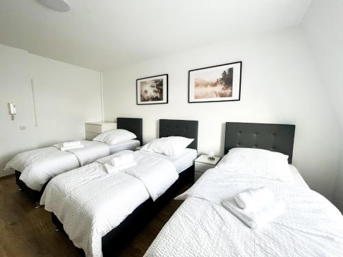 three beds in a room with white sheets at Krefeld House Deluxe Apartment - 15min to DUS & FREE Parking in Krefeld