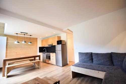 un salon avec un canapé bleu et une cuisine dans l'établissement Résidence Le France - DUPLEX 9 PERS - LE FRANCE - PLAGNE CENTRE MAE-9444, à Aime La Plagne