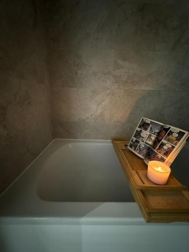 a bath tub in a bathroom with a candle and a book at Stokes Croft - Whole Apartment - City Centre - Serviced Accommodation BS1 in Bristol