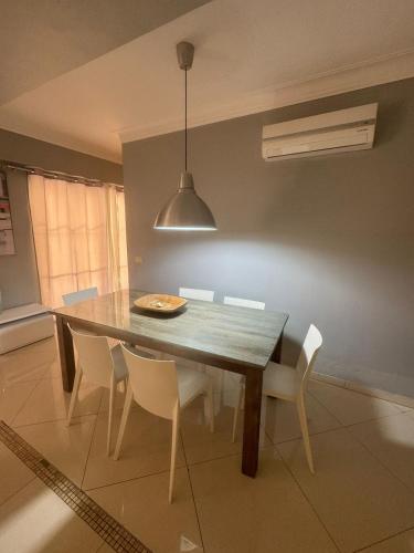 a dining room table with white chairs and aendant light at Las Palmeras by Graziano in Boca Chica