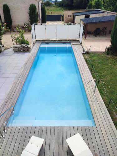 une grande piscine bleue sur une terrasse en bois dans l'établissement Maison des Hauts, terre de lavoirs, à La Crèche