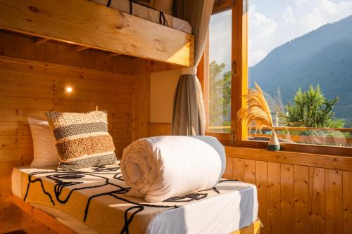 a bed in a wooden room with a window at Olgah Manali in Manāli