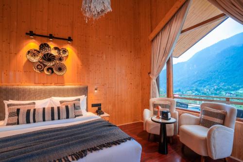 a bedroom with a bed and two chairs and a window at Olgah Manali in Manāli
