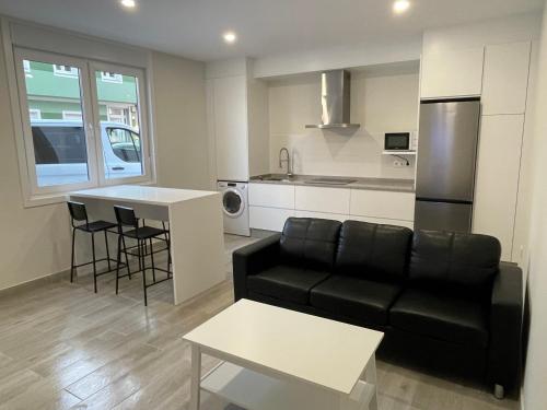 a living room with a black couch and a kitchen at Camiño da Camposa in Muxia