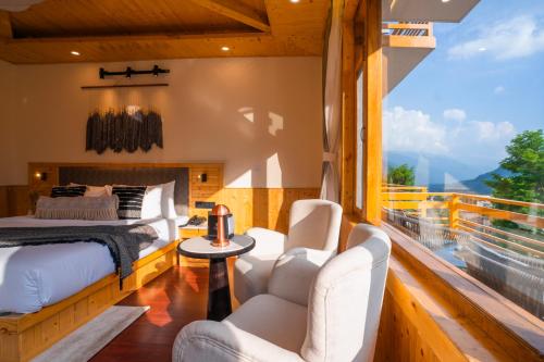 a bedroom with a bed and chairs and a balcony at Olgah Manali in Manāli