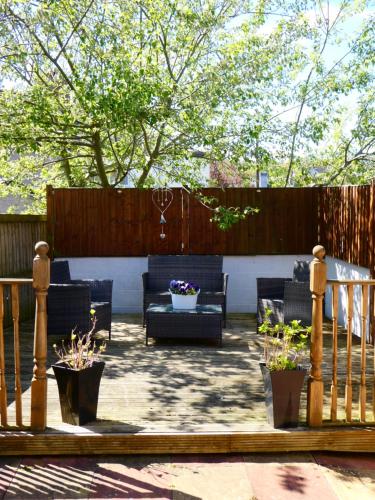 a patio with furniture and potted plants and a fence at Fern Villa in Conwy