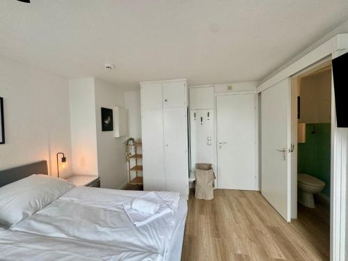a bedroom with a white bed and a bathroom at gina stay - Ferienwohnung 200m vom Strand in Büsum in Büsum