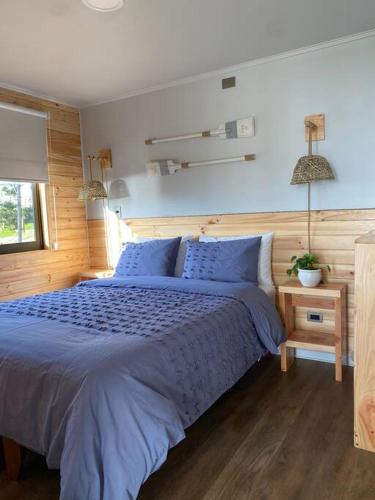 a bedroom with a large bed with blue sheets at Casa Serena frente a la playa, vista panorámica, sector Cardonal, Pelluhue in Pelluhue