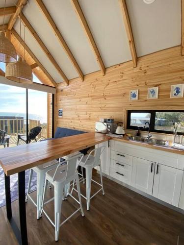 a kitchen with a long wooden table and white chairs at Casa Serena frente a la playa, vista panorámica, sector Cardonal, Pelluhue in Pelluhue