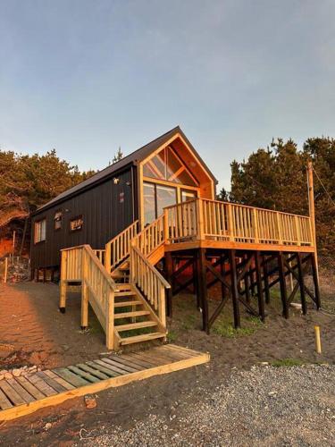 a large wooden house with a staircase in front of it at Casa Serena frente a la playa, vista panorámica, sector Cardonal, Pelluhue in Pelluhue