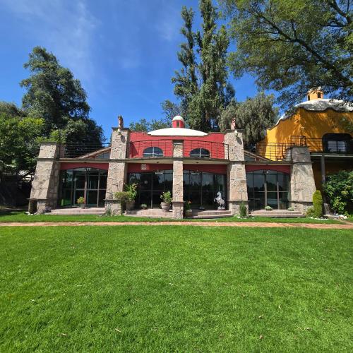 una casa con techo rojo sobre un césped verde en Hacienda La Skondida Hotel Resort, en San Mateo Xoloc