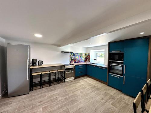 une cuisine avec des armoires bleues et un comptoir dans l'établissement Le Gîte 21 - Grande Maison pour Groupes, à Vallon-Pont-dʼArc