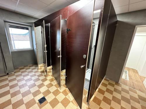 une salle de bains avec des stalles dans une pièce dotée de carrelage. dans l'établissement Le Gîte 21 - Grande Maison pour Groupes, à Vallon-Pont-dʼArc
