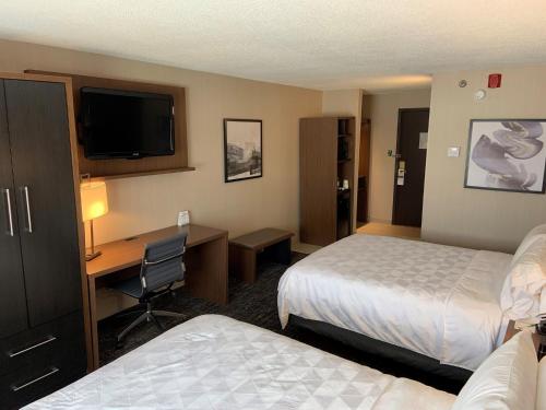a hotel room with two beds and a desk with a computer at Holiday Inn & Suites Chicago-Carol Stream Wheaton by IHG in Carol Stream