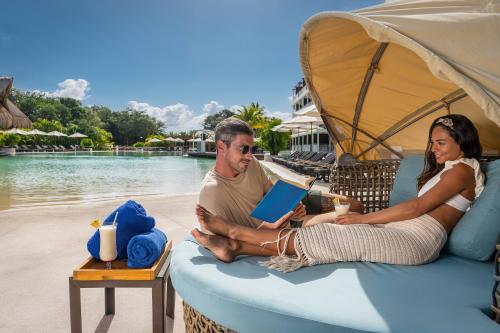 a man and a woman sitting on a recliner by a pool at El Beso Adults Only at Ocean Riviera Paradise All Inclusive in Playa del Carmen