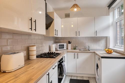 a kitchen with white cabinets and a stove top oven at Contractors & Relocation haven, 3BD House, Secure off-site parking & office space in Manchester