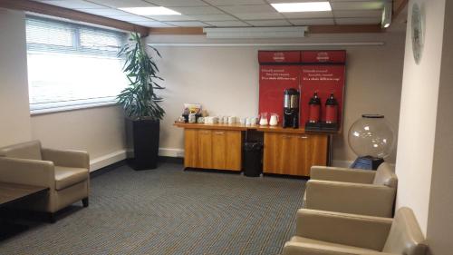 a waiting room with chairs and a counter with bottles of wine at Holiday Inn Derby/Nottingham by IHG in Derby
