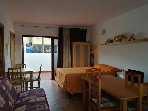 ein Schlafzimmer mit einem Bett, einem Tisch und Stühlen in der Unterkunft Estudio con terraza in La Caleta