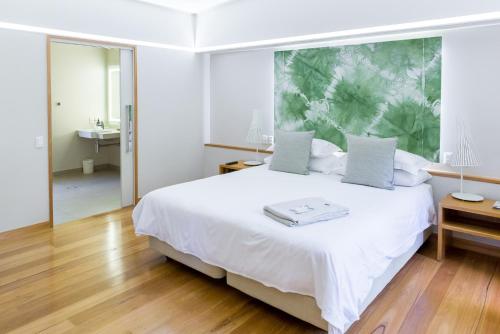 a bedroom with a white bed with a large painting on the wall at Elements Of Byron in Byron Bay