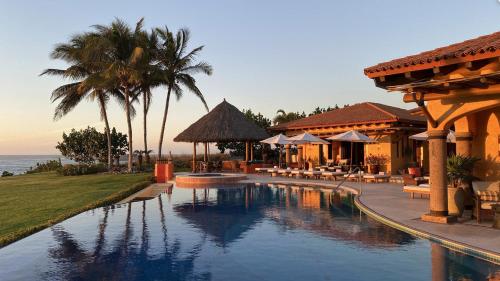 a swimming pool in a resort with tables and chairs at Estate Casas Enjoy 3000 USD Credit For Your Holiday Stay in Punta Mita