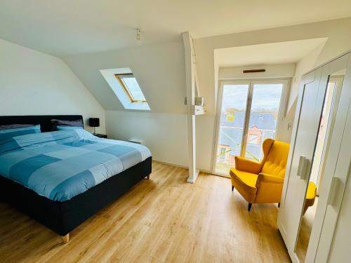 a bedroom with a bed and a yellow chair at Grand Duplex à 400m de la plage in Saint-Aubin-sur-Mer