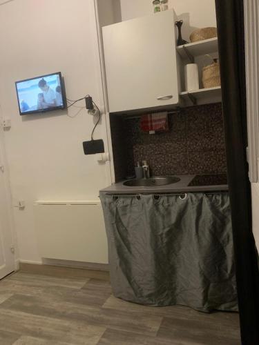 une cuisine avec un évier et une télévision sur une porte. dans l'établissement Studio Paris Charonne, à Chennevières-sur-Marne