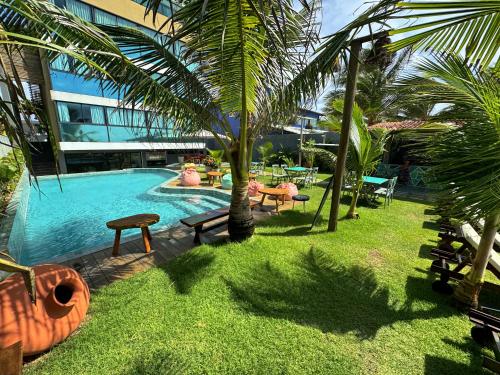 a swimming pool with palm trees and a building at Rudá Boutique Hotel Porto de Galinhas in Porto De Galinhas