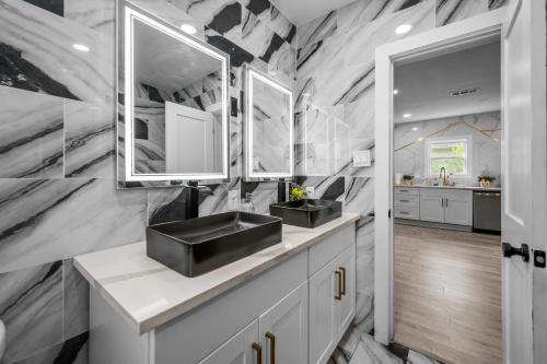 a bathroom with two sinks and two mirrors at Modern & Spacious 3BR Retreat on Prime Location in Houston