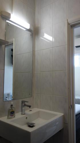 a white bathroom with a sink and a mirror at Abbey Point Hotel in London