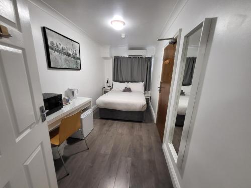 a small room with a bed and a desk and a bed sidx sidx sidx sidx at Abbey Point Hotel in London