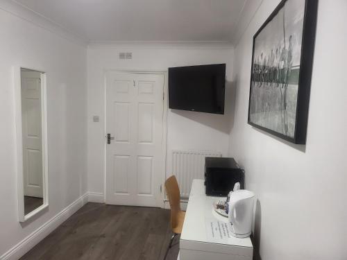 a white room with a desk and a television on the wall at Abbey Point Hotel in London