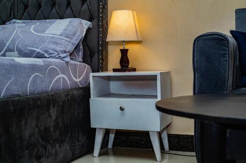 a nightstand with a lamp and a table next to a bed at Well lit and loaded studio bnb in Kikuyu