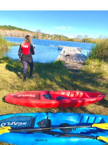 a woman standing next to a red kayak next to a lake at cabaña, casa de campo IKIGAI in Quillón
