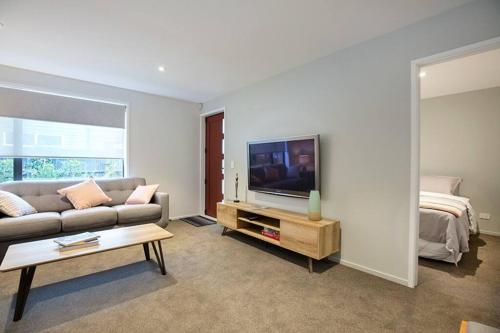 a living room with a couch and a tv and a bed at Home from home Central City Apartment in Christchurch