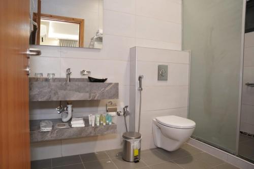 a bathroom with a toilet and a sink and a mirror at أوتار ذهب للشقق الفندقية الفاخرة in Ma‘ān
