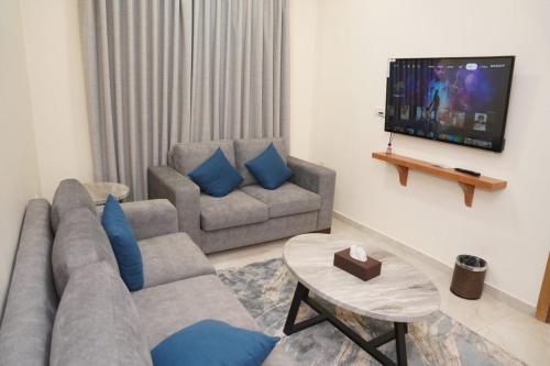 a living room with a couch and a tv at أوتار ذهب للشقق الفندقية الفاخرة in Ma‘ān