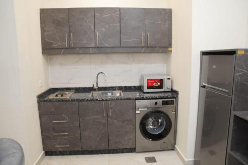 a kitchen with a sink and a washing machine at أوتار ذهب للشقق الفندقية الفاخرة in Ma‘ān