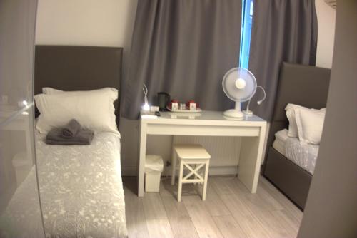 a small bedroom with a bed and a desk at Abbey Point Hotel in London