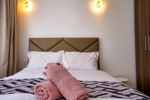 a pink teddy bear laying on top of a bed at House of DC- stylish 2 bedroom apartment in Kahawa