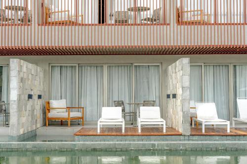 a group of white chairs and a table and some water at île de Pipa - Ma Plage Hotel in Pipa