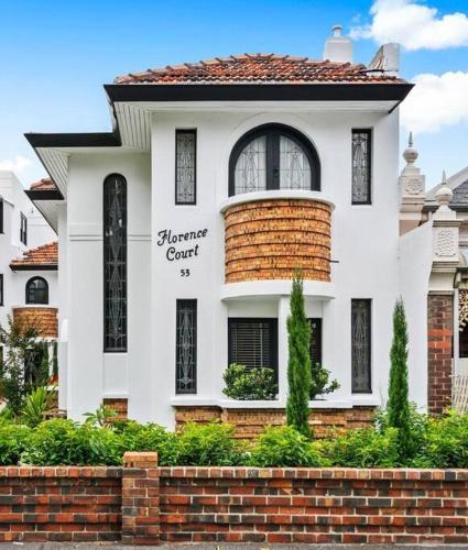 a white house with a brick wall in front of it at Art Deco Boutique Bespoke Brilliance & Beach&Park in Melbourne