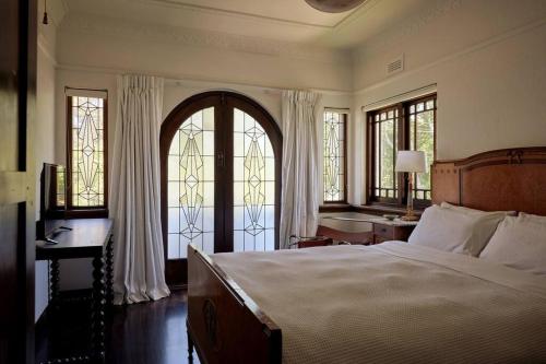 a bedroom with a bed and a desk and windows at Art Deco Boutique Bespoke Brilliance & Beach&Park in Melbourne