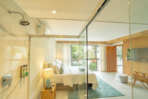 a bedroom with a bed and a glass wall at île de Pipa - Ma Plage Hotel in Pipa