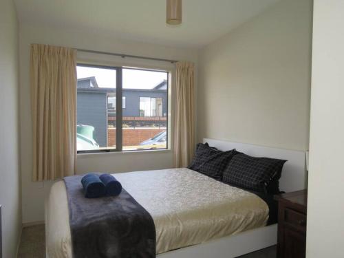 a bedroom with a bed and a large window at Cleggs Batch in Karikari Peninsula
