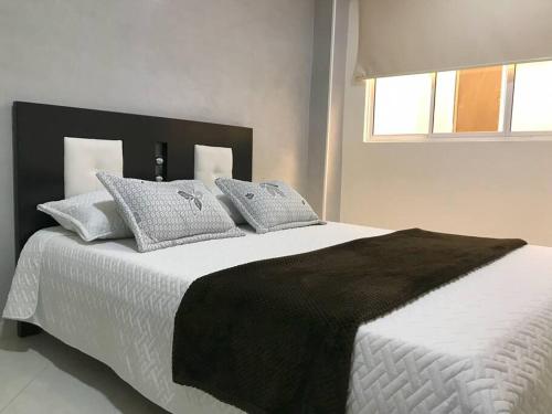 a bedroom with a large bed with white sheets and pillows at Encantador apto en Barrancabermeja in Barrancabermeja