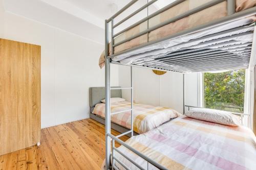 a bedroom with two bunk beds and a window at 52 Ballingalla Street, Narooma in Narooma